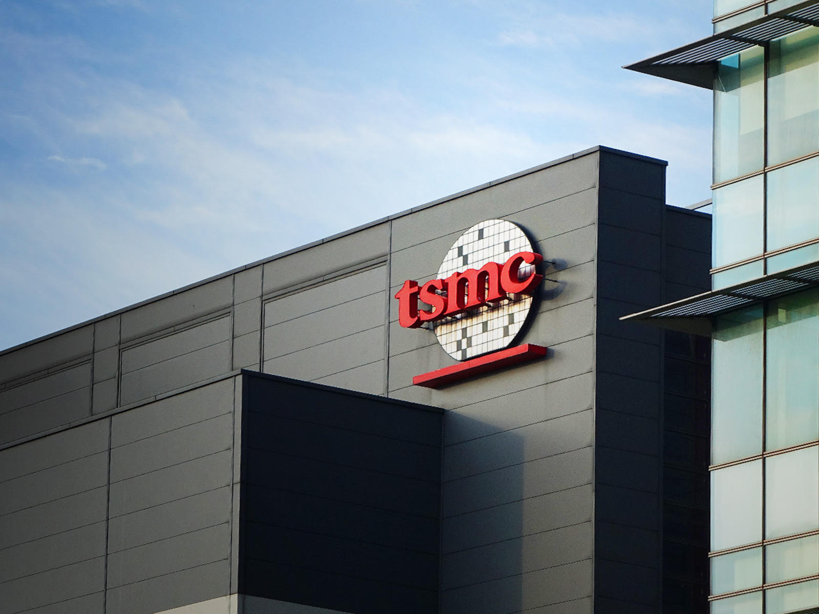Bir TSMC üretim tesisinin dış cephesi ve çatısındaki kırmızı şirket logosu.