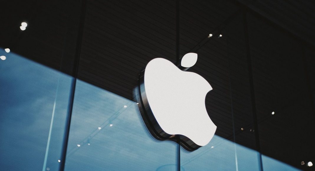 Camlı bir Apple mağazasının cephesindeki beyaz Apple logosu; arkada mavi gökyüzü.