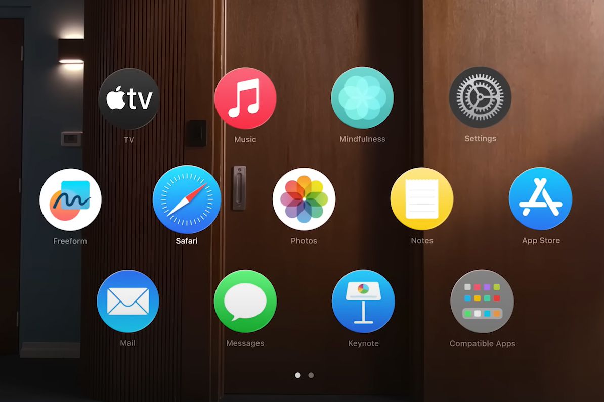 Apple Vision Pro ana ekranı: ahşap kaplı bir odanın önünde havada duran daire biçimli uygulama simgeleri.